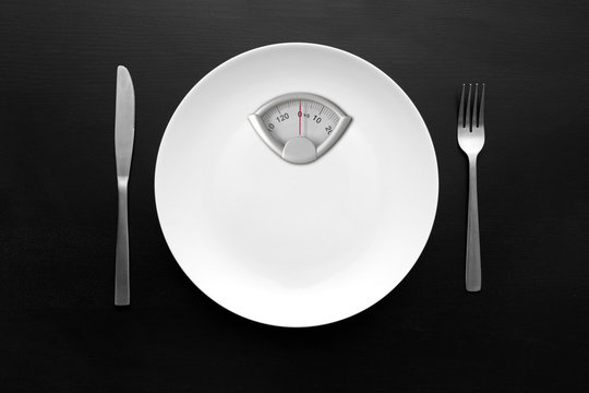 dieting concept - white plate with weight scale