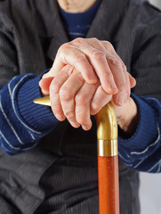 Elderly hands resting on stick