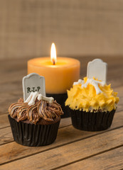 Colorful Halloween cupcakes and candle on rustic wooden table