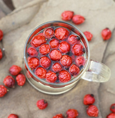 transparent glass cup of herbal tea with dried rose hips on a ta