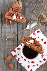 Chocolate biscotti with almonds and cup of coffee on a wooden ta