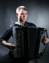 musician plays the accordion against a dark background