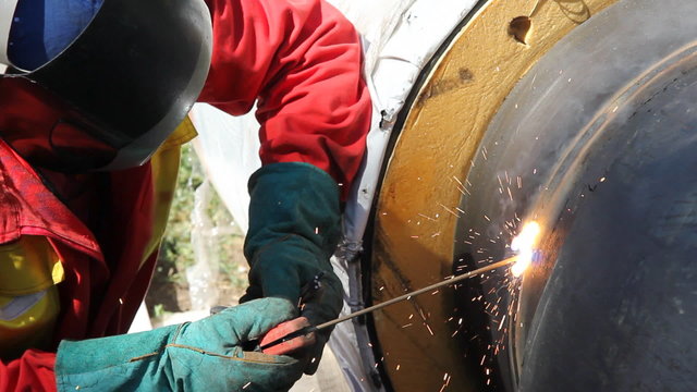Welder at work, welding pipe