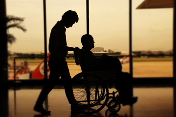 Asistente llevando en silla de ruedas a un viajero en la terminal de un aeropuerto