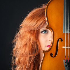 Young woman with violin against black background.