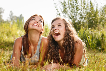 two girlfriends lying down on grass