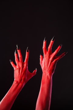 Red devil hands with sharp black nails, real body-art