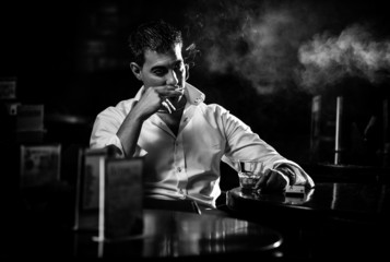 Black and white portrait of man smoking cigarette in restaurant