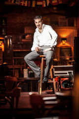 Fototapeta na wymiar Handsome man sitting on chair on stage at bar