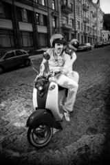 Black and white photo of man riding girlfriend on scooter