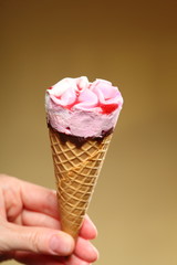 Berry icecream cone in hand on brown