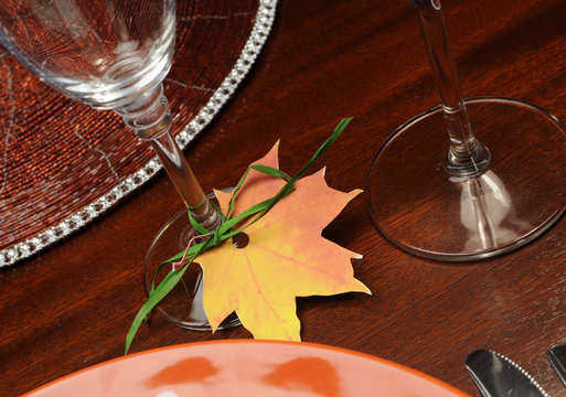 Close up on Thanksgivng place setting autumn leaf at glass base