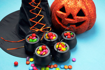 Halloween black witch hat and cauldrons full of candy with pumpk