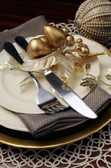 Closeup gold theme Christmas dinner table place setting