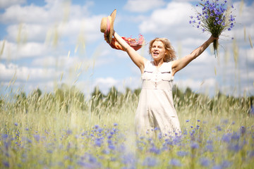 Naklejka na ściany i meble Happy woman in corn field with cornflowers