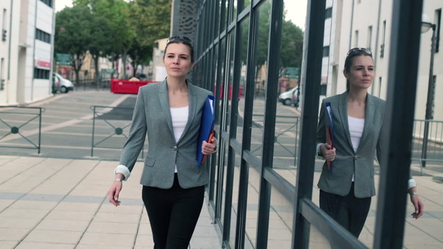 Young confident businesswoman walking by office building