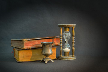 Vintage books and hourglass in dark room