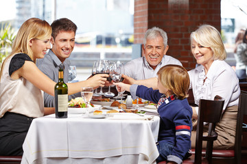 Familie im Restaurant prostet sich zu