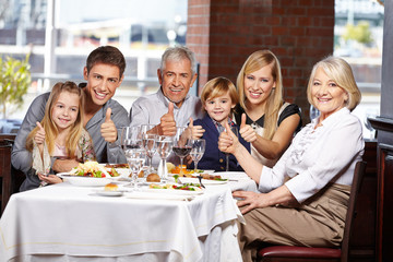 Familie im Restaurant hält die Daumen hoch