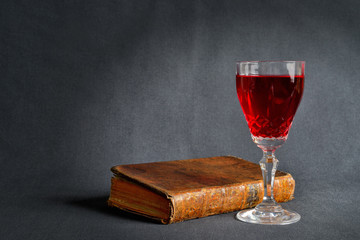 Old book in leather binding and a glass of re wine