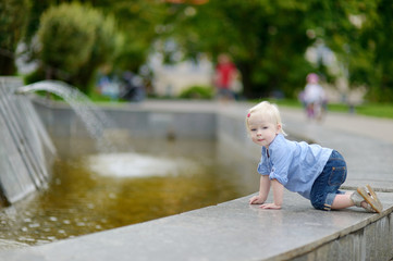 Toddler girl having fun by a city fountain