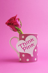 "Think pink" message with rose bud on coffee cup