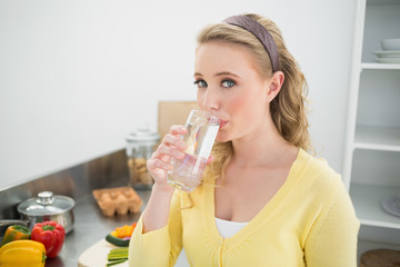 Content cute blonde drinking a glass of water