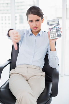 Disappointed classy brown haired businesswoman showing her calcu