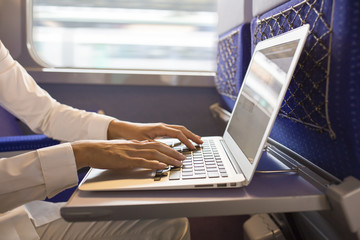 Close-up woman hands typing on a laptop keyboard in the train