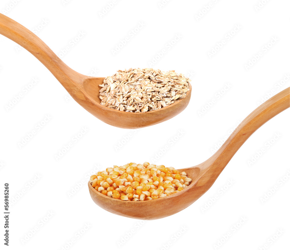 Wall mural Wooden spoons with oatmeal flakes and corn grains.