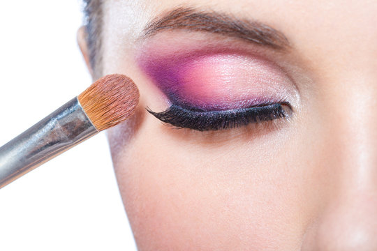 Close up of brush applying bright pink makeup