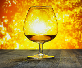 Glass of brandy on evening sky background