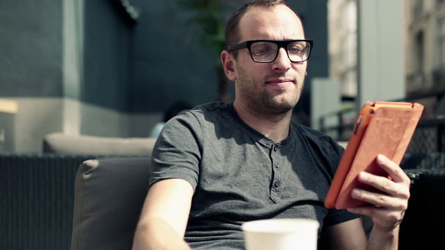 Man with tablet computer drinking coffee in cafe