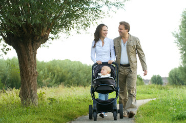 happy mother and father walking with baby in pram