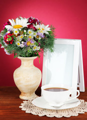 Beautiful bright flowers in vase on table on pink background