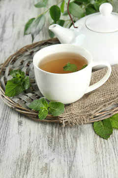Teapot and cup of herbal tea with fresh mint on wooden table