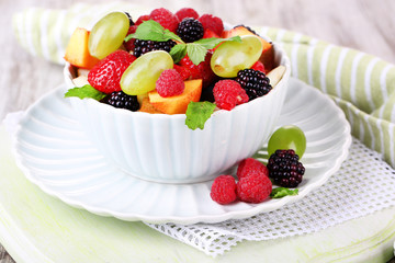 Fruit salad in bowl, on wooden background