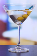Martini with green olives on table in bar