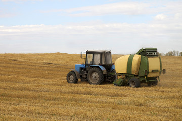 Obraz premium Rolls of straw and tractor