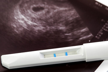 positive pregnancy test and ultrasound of baby in mother's womb