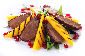 Salad with duck fillet and grilled mango on white background.