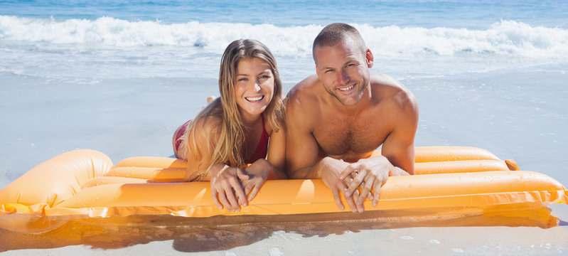 Happy cute couple in swimsuit lying on the beach
