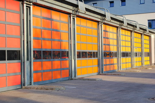 Rote, gelbe und orange Garagentore eines Feuerwehrhauses