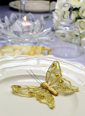 Wedding dining table setting with gold butterfly on plate