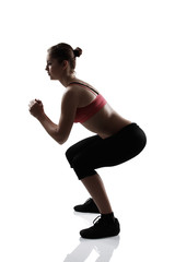 sport girl doing squatting exercise, silhouette studio shot over