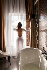 Attractive woman looking at window and preparing to take a bath