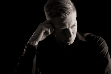 Black and white portrait of young likable man, low key.