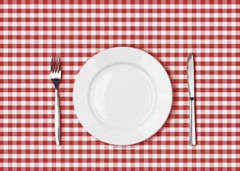 Knife, white plate and fork on red picnic table cloth