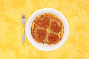 A small pepperoni pizza meal on a yellow tablecloth