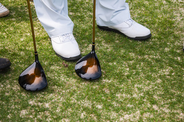 2 drivers and 1 pair of white golf shoes